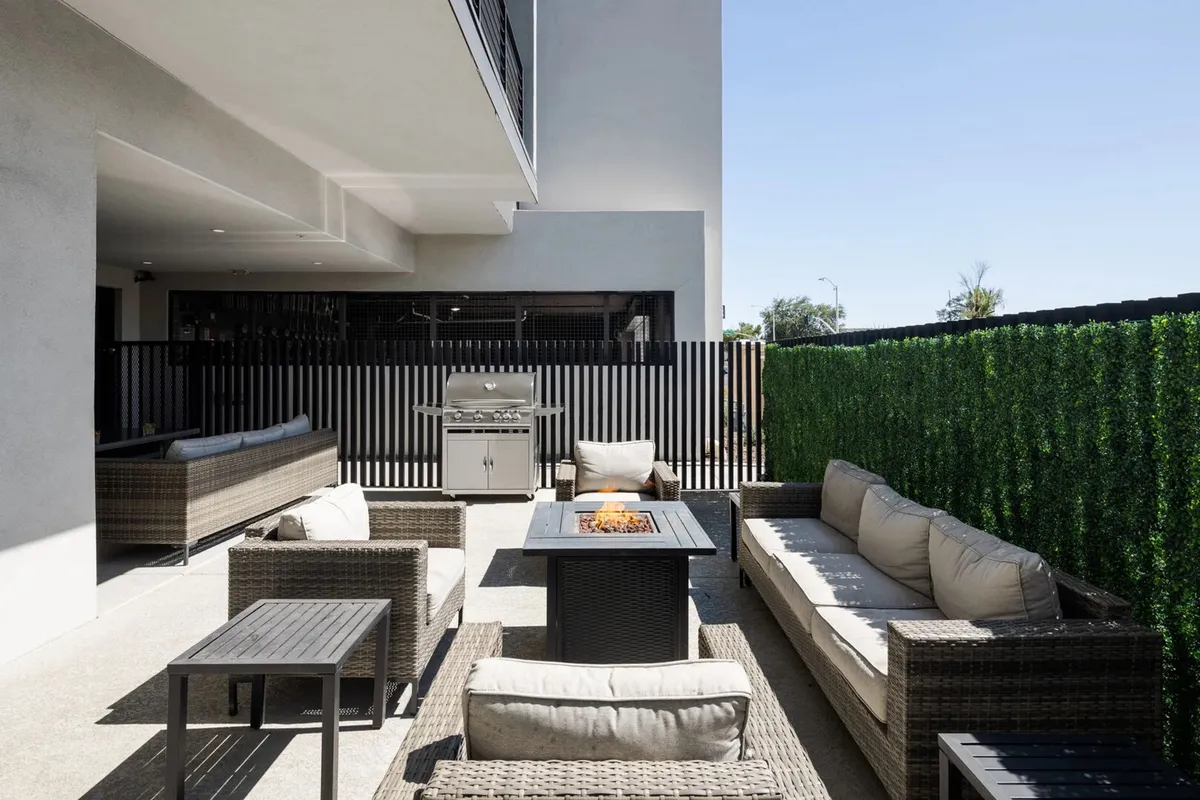 This exterior image features a fire pit surrounded by outdoor seating and a built-in grill, with a welcoming setting for barbecues and evenings under the stars. The space is designed for socializing, dining, and enjoying the warmth of the fire pit.