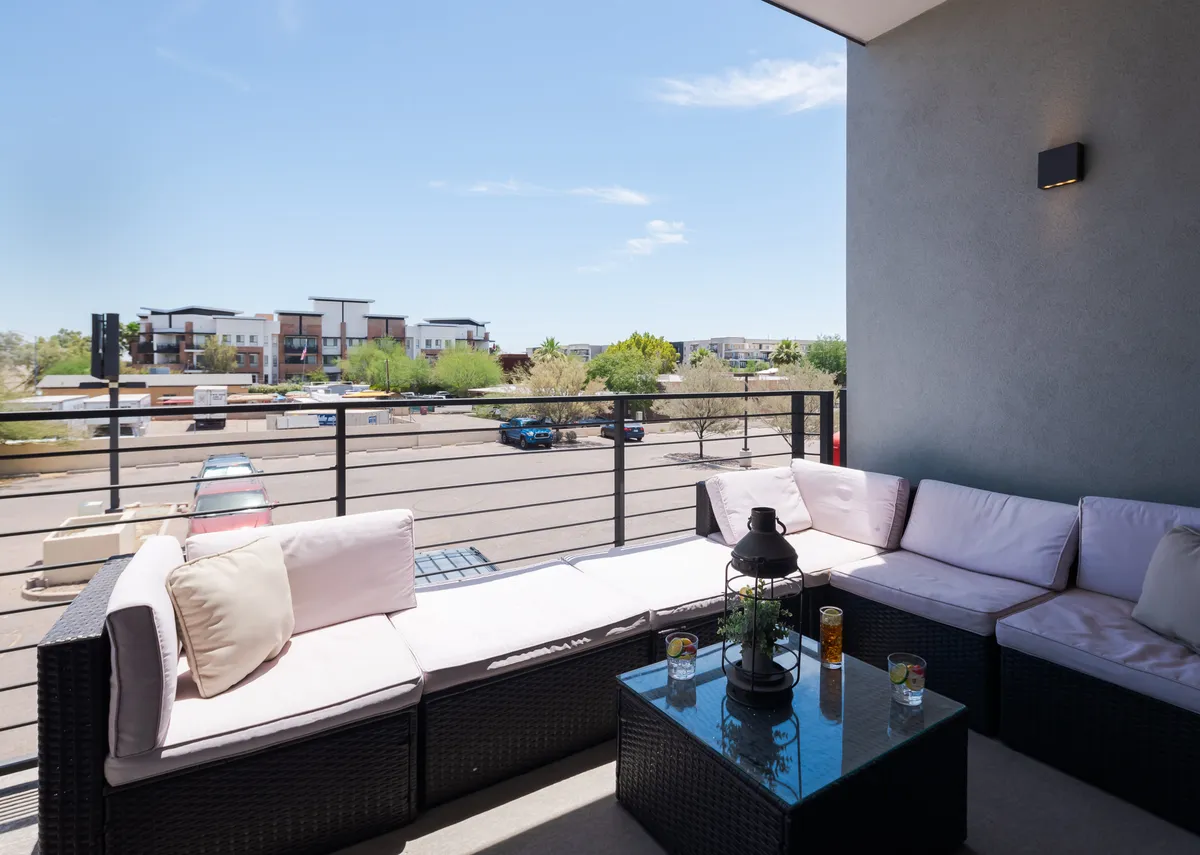 An inviting outdoor seating area with a glass table and decorative lantern, set against a serene backdrop. The enclosed feel hints at privacy and a secure environment, making it ideal for unwinding after arrival.