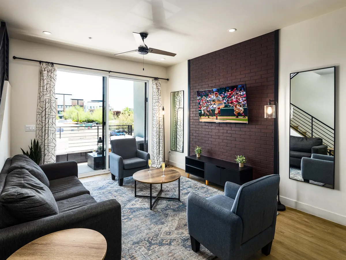 A casual living space featuring a comfortable sofa, a coffee table, and a television, opening up to a balcony with a view. The atmosphere is relaxed and bright, making it a great spot for socializing or enjoying a quiet moment with a view.